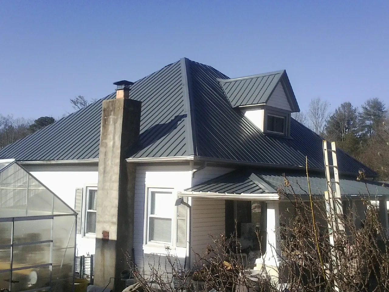 Dark blue standing seam metal roof on a white farmhouse with dormer — Slate & Tile Roof Repair by Roofing Brothers in Stephentown