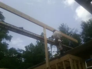 Carpenter setting a ridge beam over a new addition frame — Ice Dam Removal by Roofing Brothers in Stephentown