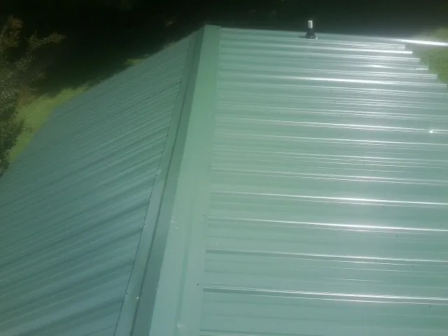 New green metal panels meeting at the ridge of a roof — Flat Roof Repair work by our crew in Stephentown