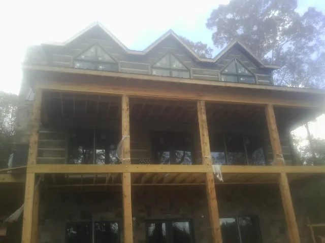Dormers and porch framing on a large log home under construction — Roof Coating work by our crew in Stephentown