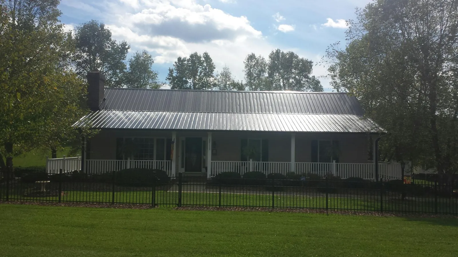 Gray metal roof on a brick ranch with a full width front porch — Gutter Guard Installation work by our crew in Stephentown
