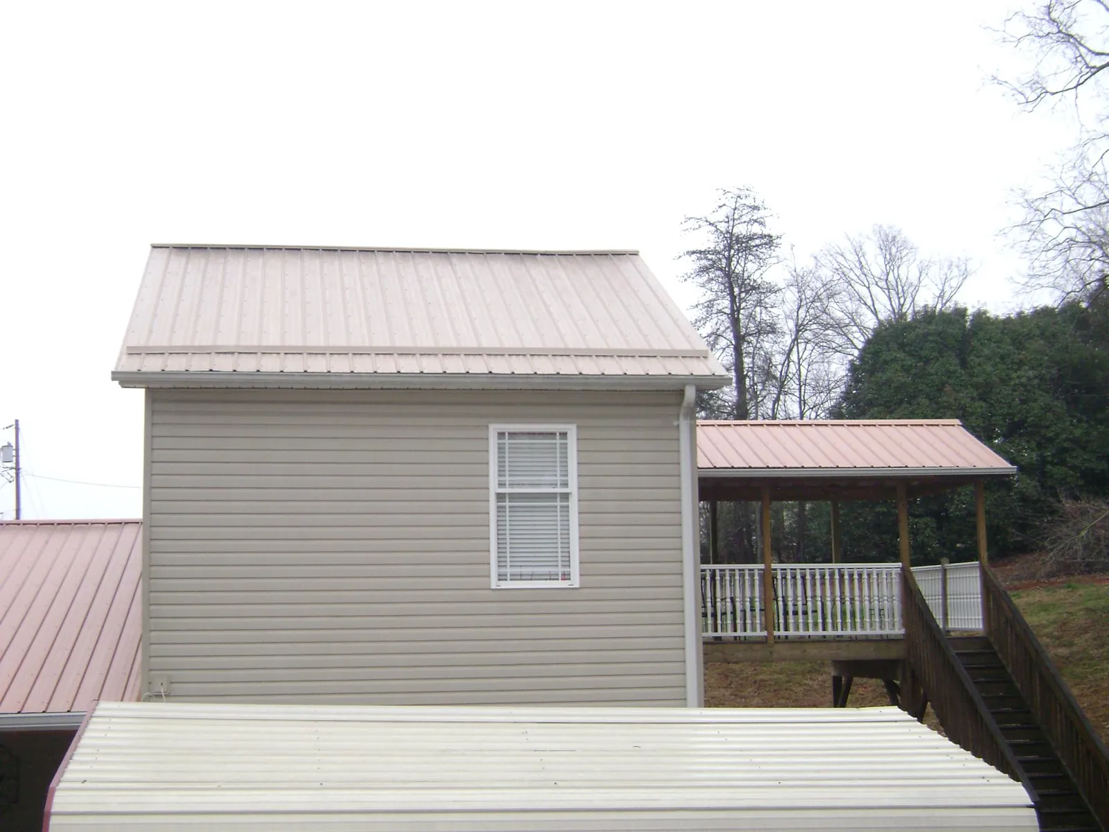 Tan metal roofs on a two story addition and attached porch, from a Roof Replacement job in Stephentown