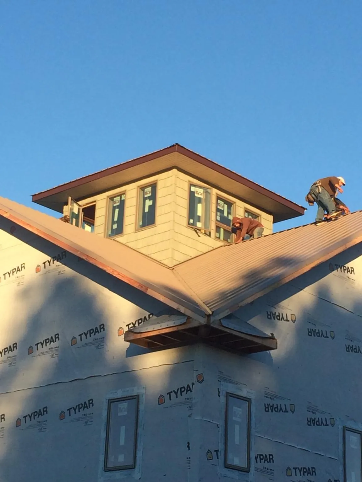 Roofers working around a rooftop cupola on a new metal roof at sunset — Roof Waterproofing in Stephentown by Roofing Brothers